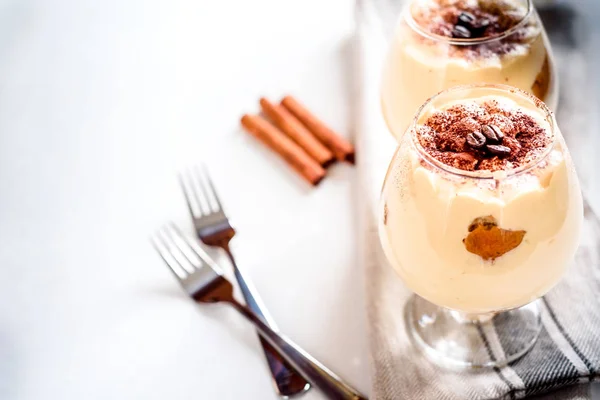 Exquisite Italian dessert tiramisu in cognac glasses on a white — Stock Photo, Image