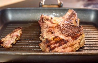 Büyük parça üzerinde ızgara tava hazırlanan taze sığır eti biftek.