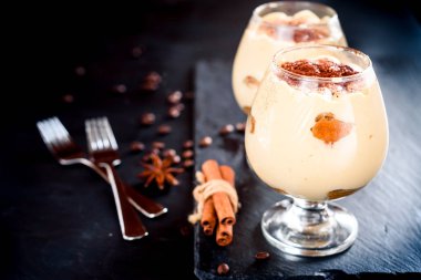 karanlık bir arka plan üzerinde kahve çekirdekleri ile dekore edilmiş bir cam tiramisu