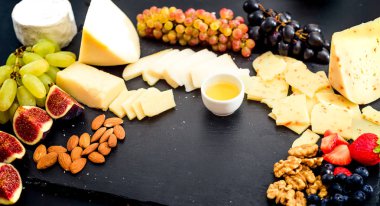Peynir tabağı. Ceviz, badem, üzüm, incir, çilek, yaban mersini ve taş tabakta bal ile peynir çeşitleri