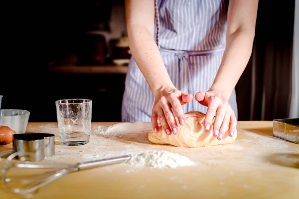 Mãos femininas fazendo massa na mesa de madeira — Fotografia de Stock