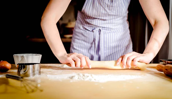 Vrouwelijke handen rollen deeg uit op keukentafel, close-up — Stockfoto