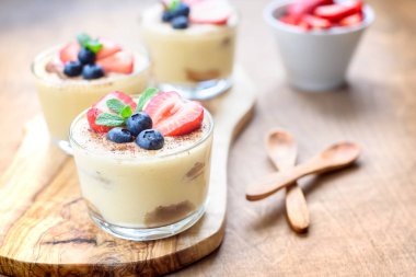 Gözlüklü ev yapımı, enfes tatlı tiramisu çilek, yaban mersini, nane ile dekore edilmiş beyaz ahşap tablo