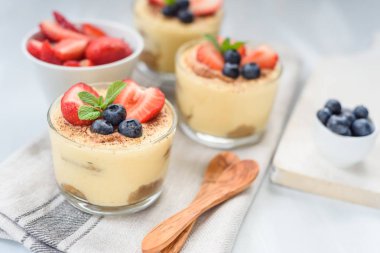 Gözlüklü ev yapımı, enfes tatlı tiramisu çilek, yaban mersini, nane ile dekore edilmiş beyaz ahşap tablo