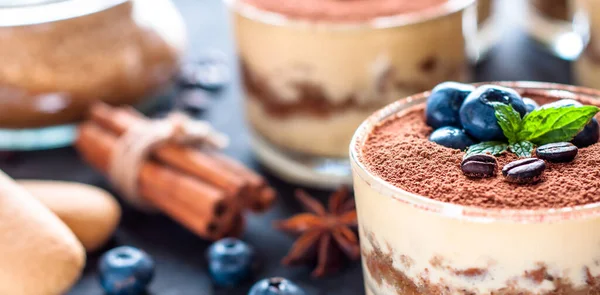 Dessert tiramisu in glazen, versierd met bosbessen en munt met koffiebonen, het concept van het heerlijke leven — Stockfoto