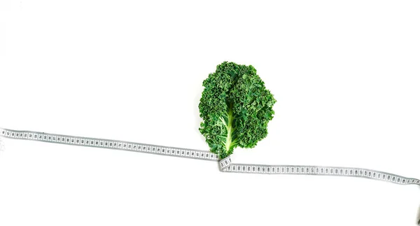 Kale dibungkus dalam pita ukur, konsep diet, slimming, sehat makan top view, pada latar belakang putih — Stok Foto
