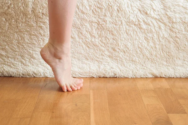 Mooie vrouwenvoeten en -benen op houten vloer en witte achtergrond — Stockfoto