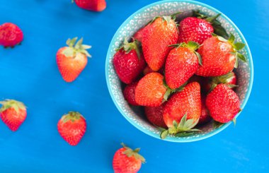 Renkli arka planda renkli bir kasede çilekler.