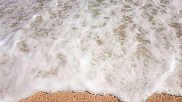 Abstracte achtergrond van zee golven, op goudkleurig zand, wit zeeschuim, zonlicht — Stockfoto