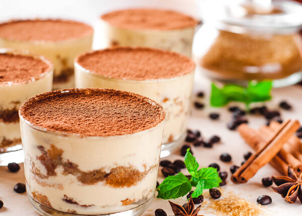 classical tiramisu dessert in a glass sprinkled with cocoa and decorated with coffee beans on a wooden background, luxury dessert