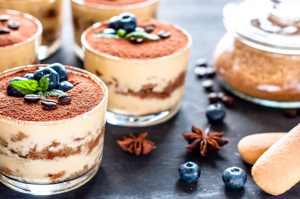 Makanan penutup tiramisu dalam gelas, dihiasi dengan blueberry dan mint dengan biji kopi, konsep hidup yang lezat — Stok Foto