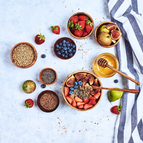 Здоровый завтрак и завтрак ингредиенты, овсянка с фруктами и ягодами, инжир, черника, клубника, семена льна и чиа, мед. Вид сверху, плоский — стоковое фото