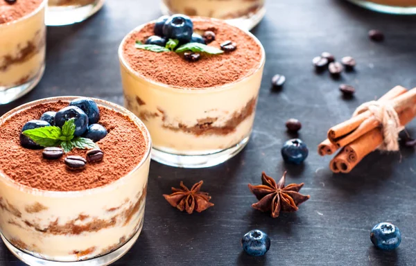 Dessert tiramisu in glasses, decorated with blueberries and mint with coffee beans. — Stock Photo, Image