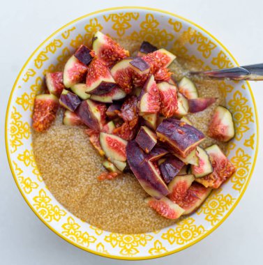 Gluten free amaranth porridge for breakfast with figs in a yellow bowl top view