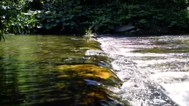 Wiosenna rzeka w mieście płynąca między skałami, ludzie na moście w tle, zwolnione tempo — Wideo stockowe