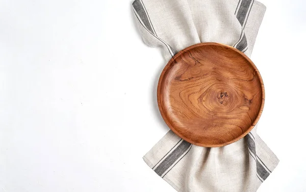 Коричневая деревянная тарелка на полотенце, на голубом столе, вид сверху — стоковое фото