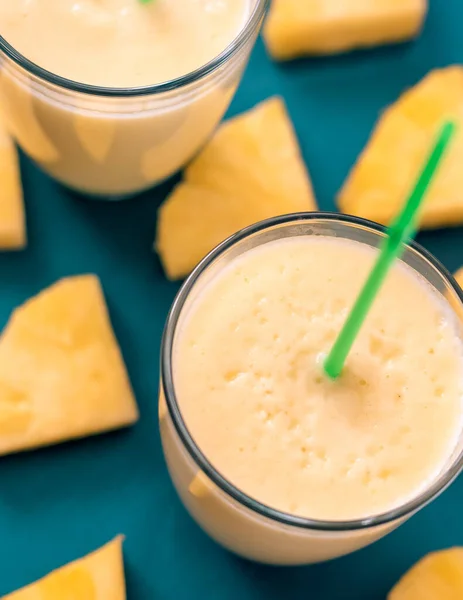 Zumo de piña fresca en un vaso con una paja sobre un fondo azul y verde — Foto de Stock