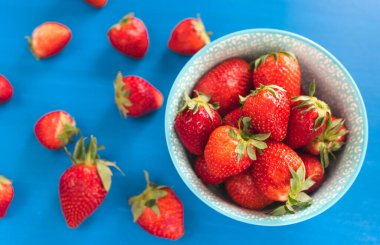 Renkli arka planda renkli bir kasede çilekler.