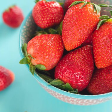 Renkli arka planda renkli bir kasede çilekler.