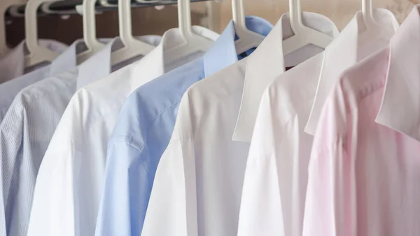 Las camisas planchadas multicolores de los hombres cuelgan en una percha, foco selectivo — Foto de Stock