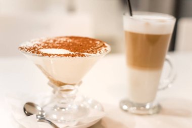 Kakao serpilmiş bir bardakta tiramisu, kaşık kalıntısı.