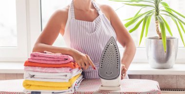 Elbiselerini ütüleyen güzel bir kadın. Ev işleri.
