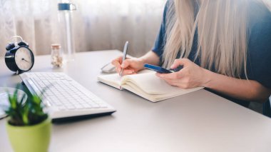 Kız elinde bir spartphone tutuyor ve not alıyor.