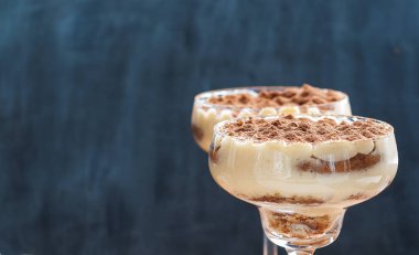 Kokteyl bardaklarında kakao tozuyla süslenmiş lüks tiramisu.