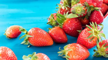 taze parlak çilek mavi arka plan üzerinde kase dışarı dökülen