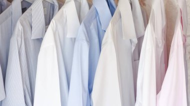 Çok renkli ütülü erkek gömlekleri askıda asılı.