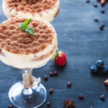 Kokteyl bardaklarında kakao tozuyla süslenmiş lüks tiramisu.