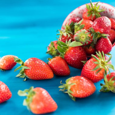 taze parlak çilek mavi arka plan üzerinde kase dışarı dökülen