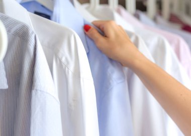 Çok renkli ütülü erkek gömlekleri askıda asılı.