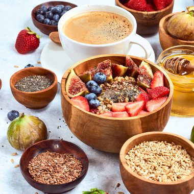 Sağlıklı kahvaltı ve kahvaltı malzemeleri, meyve ve çilek, incir, yaban mersini, çilek, keten ve chia tohumu, bal ile yulaf ezmesi.