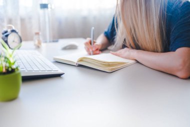 Kız deftere yazıyor, haftanın programını çiziyor.