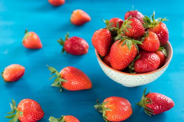 taze parlak çilek mavi arka plan üzerinde kase dışarı dökülen