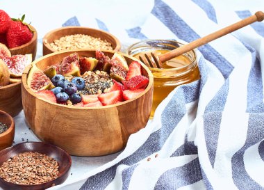 Sağlıklı kahvaltı ve kahvaltı malzemeleri, meyve ve çilek, incir, yaban mersini, çilek, keten ve chia tohumu, bal ile yulaf ezmesi.