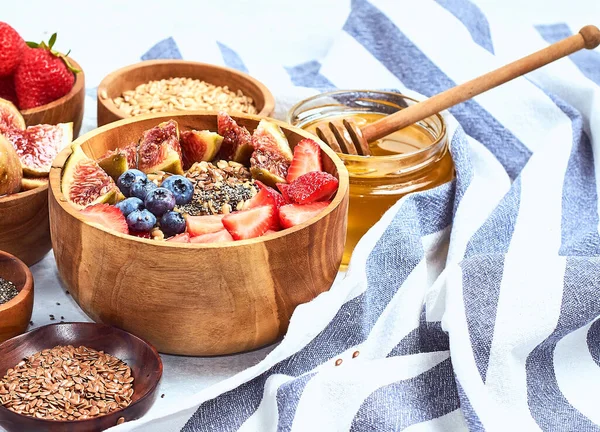 Sağlıklı kahvaltı ve kahvaltı malzemeleri, meyve ve çilek, incir, yaban mersini, çilek, keten ve chia tohumu, bal ile yulaf ezmesi.