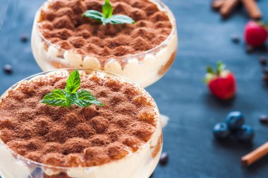 Kokteyl bardaklarında kakao tozuyla süslenmiş lüks tiramisu.