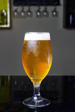Bira dolu bir bardak, bira ya da chopp ile, bir barda siyah bir masanın üzerinde.