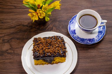 Çikolata kremalı havuçlu kek ve tahta masada bir fincan kahve..