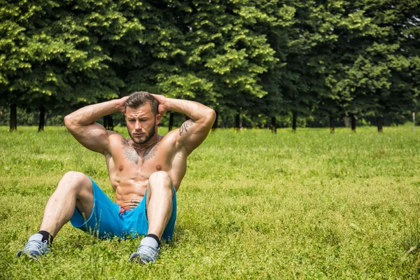 Bearded sportsman doing abs exercise in park — Stock Photo, Image