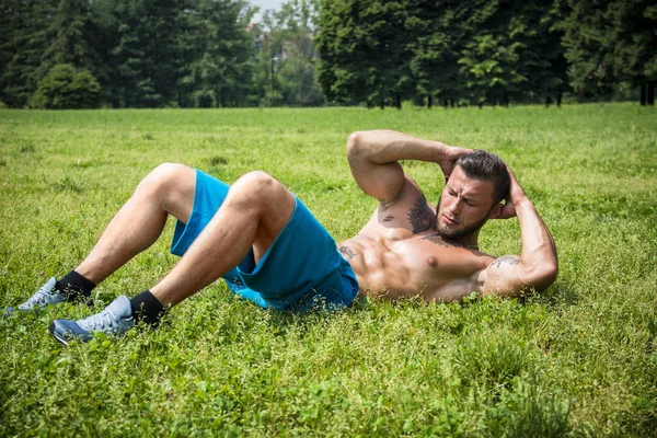 Bearded sportsman doing abs exercise in park — Stock Photo, Image