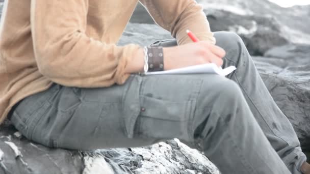 Joven escribiendo y pensando frente al mar — Vídeo de stock