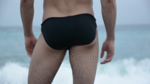 Homem em calções de banho em pé no litoral — Vídeo de Stock