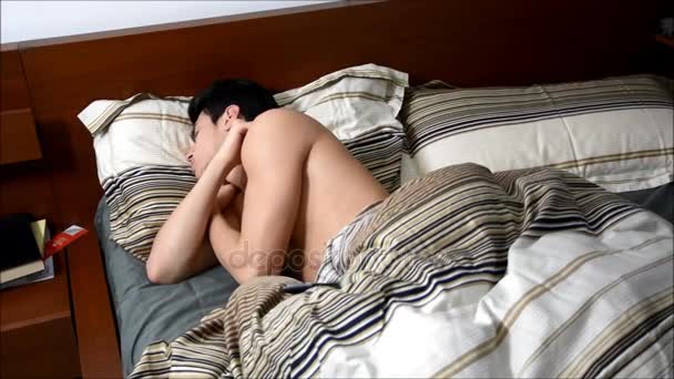 Мужчина просыпается от сна на кровати — стоковое видео