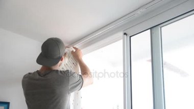 kaslı adam dikkatle perdeleri asılı