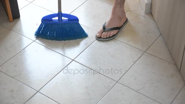 Чоловік підмітає підлогу з синьою мітлою — стокове відео