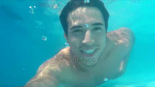 Handsome young man swimming in pool, underwater shot — Stock Video