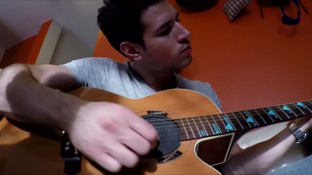 Νεαρός άνδρας στον καναπέ που παίζει κιθάρα στο σπίτι — Αρχείο Βίντεο
